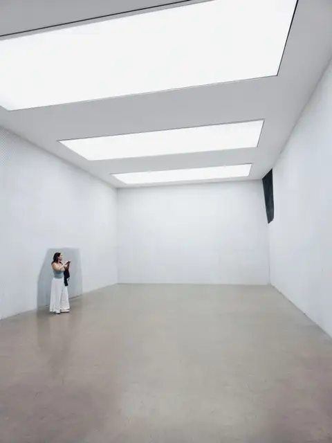 A visitor quietly observing art in a minimalist gallery space