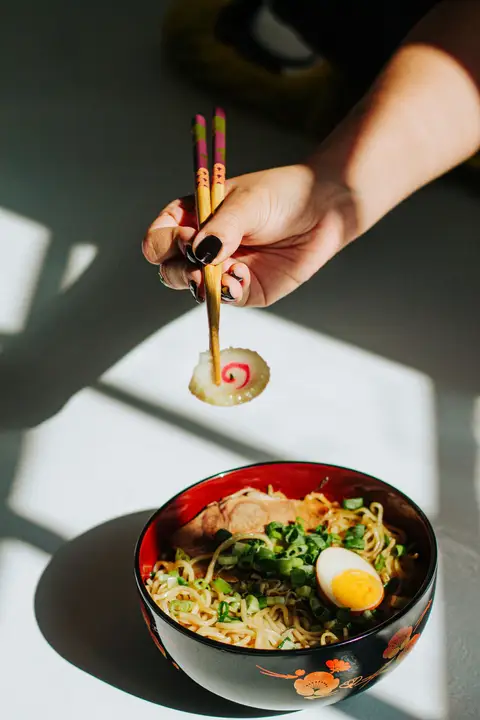 A close-up of a Japanese ramen bowl with chopsticks in natural light
